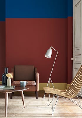 Living room painted in primary colors, red, blue and yellow with an armchair and a wooden table.