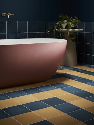 Deep blue (Royal Navy) bathroom with constrasting yellow and blue tiles and a large pink bathtub.