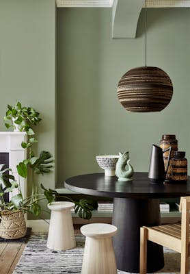 Dining area with the walls painted in calming Sage Green with a black table, stools and a chair.