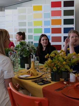 Our guests sitting at the table interacting with each other in front of a large Little Greene Colourcard.