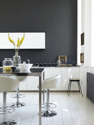 Rich black (Lamp Black) kitchen with bright white units and stools next to a black table.