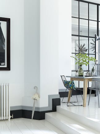 Bright white walls in 'Loft White', contrasting baseboards in Urbane Grey and Lamp Black and steps leading to a dining table.