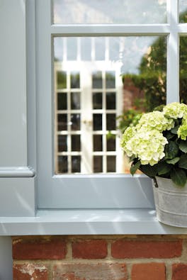 Exterior window painted in grey blue 'James' with a potted plant on the windowsill.