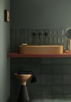 Tiled bathroom painted in grey green shade 'Livid', with contrasting sink, stool and mirror.