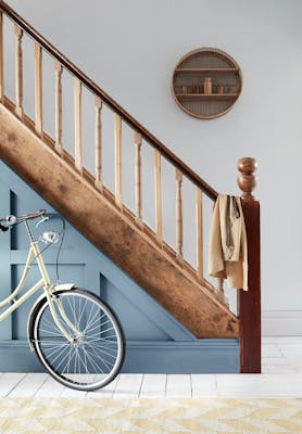 Staircase paneling in warm blue shade 'Juniper Ash' with neutral 'Wood Ash' woodwork and a bike.