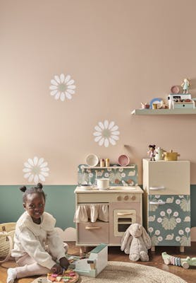 Playroom with pale pink (Masquerade) walls with a child playing with a toy cooker.