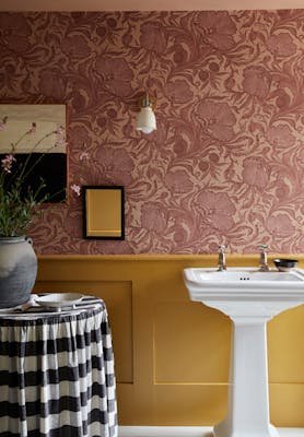 Bathroom with two-tone wall decor, featuring Poppy Trail pink floral wallpaper above and a mustard colour paint below.