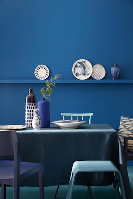 Dining room color drenched in rich blue 'Mazarine' with a dining room table and chairs.